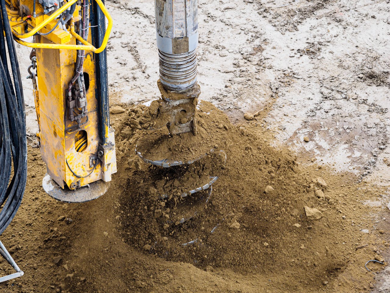 gallery-04 A close-up of a powerful drilling machine working on soil at a construction site.