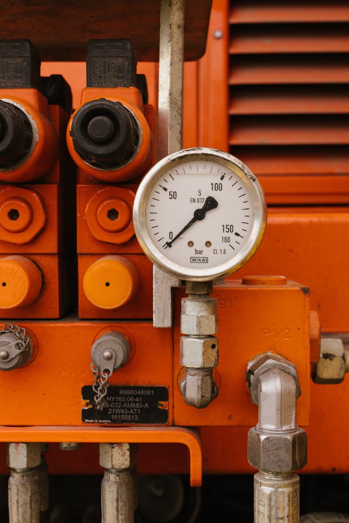 gallery-01 Detailed view of a pressure gauge on orange industrial machinery, showcasing engineering equipment.